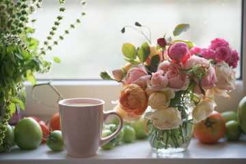A bouquet of garden roses in a glass jar on the windowsill.