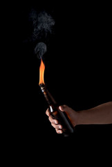 Molotov cocktail bottle with fire in the hand on a black background.