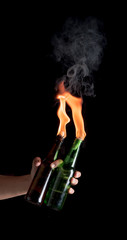 Molotov cocktail bottle with fire in the hand on a black background.