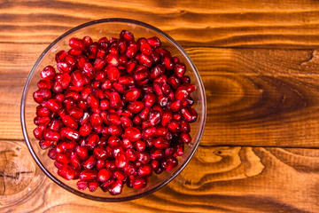 Seeds of the garnet fruit in glass bowl on wooden table. Top view