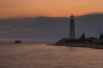 Fototapeta premium Lighthouse and sunken shipi in sea at sunset