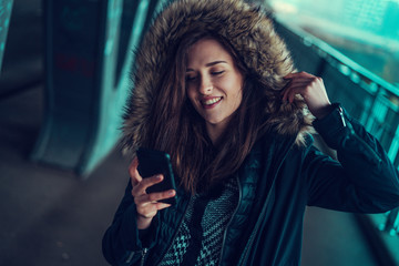 Beautiful young brunette looking at her phone under the bridge