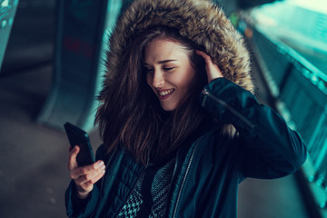 Beautiful young brunette looking at her phone under the bridge