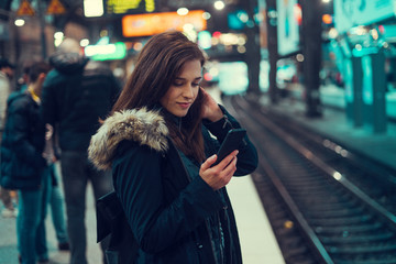 Beautiful young brunette looking at her phone under the bridge