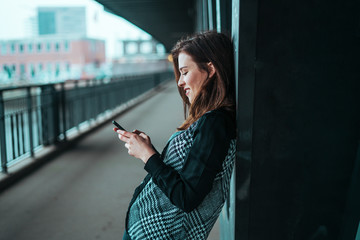 Beautiful young brunette looking at her phone under the bridge