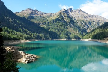 Fototapeta na wymiar paesaggio lago montagna natura riflesso acqua cime cielo azzurro riva rocce veduta scenico