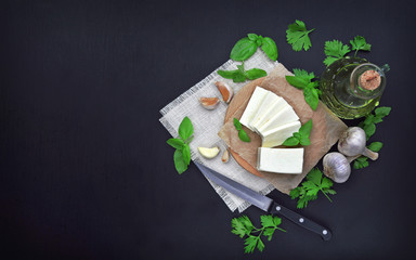 Cheese, greens and spices on a dark background. Food background. The concept of a healthy diet and lifestyle.