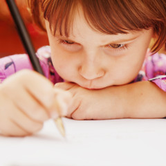 Cute serious concentrated little school girl writing notebook homework with pencil at home. Education and learning concept © zwiebackesser