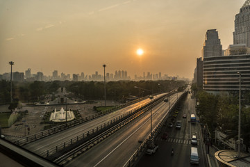Fototapeta na wymiar Sunrise Above The Bangkok City Skyline. High Buildings Behind a Park with Highway on Foreground
