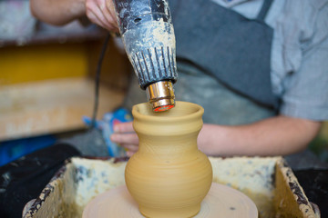 Professional male potter drying ceramic pot with special dryer in pottery workshop, studio. Crafting, artwork and handmade concept