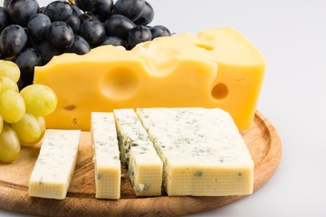 Cheeses and Grape on the Wooden Platter on the Grey Background