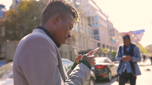 African amrican men using mobile phone in city texting dialogue with interlocutor
