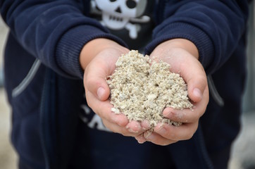 Kleinkind zeigt seine Händen, gefüllt mit Sand