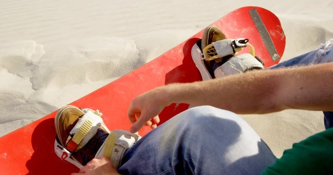 Man attaching the sand board to his footwear 4k