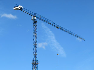 Construction crane against blue sky with white clouds