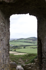 Large arched window opening in an ancient castle ruin in County Laois, Ireland giving view to a present day country landscape 