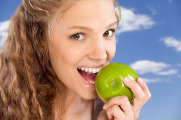 Beautiful young woman eating apple, close-up