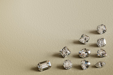 Round brilliant cut, emerald, princess, radiant. asscher, oval, cushion, heart, pear, marquise cut diamonds scattered along the corner on textured old paper background. 3D rendering