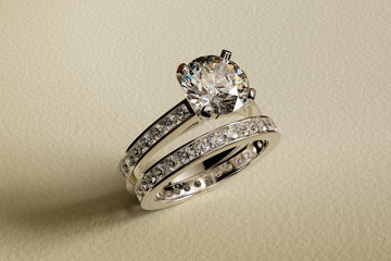 Diamond wdding set, engagement ring, eternal band with channel setting on textured beige background. 3D rendering
