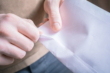 Male Hands Opening The Edge Of An Envelope - Waiting For A Message Concept