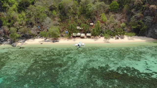 Aerial orbit drone shot around a paraw boat, anchored in turquoise waters, in front of a secret beach, at Coron island, in Philippines, Asia