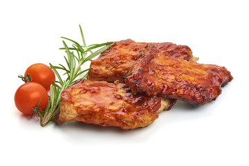 Delicious grilled pork ribs in BBQ sauce with herbs and tomatoes, isolated on white background. Close-up.