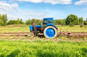 Naklejka premium Agricultural tractor working at the potato field