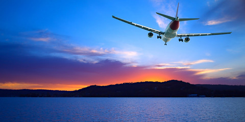 Fototapeta na wymiar Jet Airliner Flying in a crimson and blue coloured sunset sky. Queensland, Australia.
