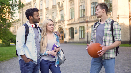 Student talking with multiracial couple near college, carefree student life