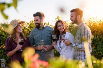 Zelfklevend Fotobehang Gelukkige vrienden die plezier hebben met het drinken van wijn bij de wijngaard van de wijnmakerij - Vriendschapsconcept met jonge mensen die samen genieten van de oogsttijd © lordn