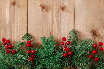 Christmas fir tree on wooden background. Red berries.