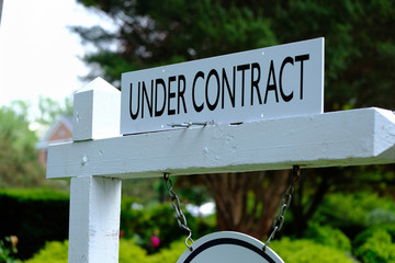 Under contract sign on wooden post. Real estate business.