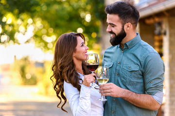 Portrait of young smiling man and woman tasting wine at winery vineyard - Young people enjoying harvest time together. Romantic love.