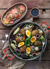 Homemade Hasselback Potatoes in a pat with root vegetables.