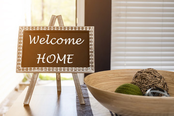 WELCOME HOME WORD BLACKBOARD ON WOODEN TABLE WITH ORANGE SUNSET LIGHT