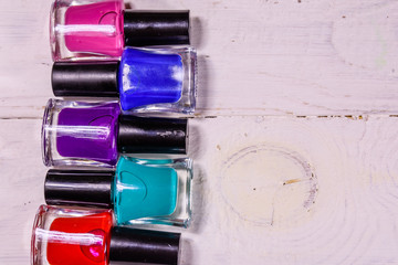 Different nail polishes on a wooden table. Top view