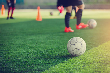 Football on green artificial turf with blurry soccer players background.