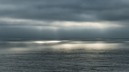 Naklejka premium Sunlight thru clouds to the ocean