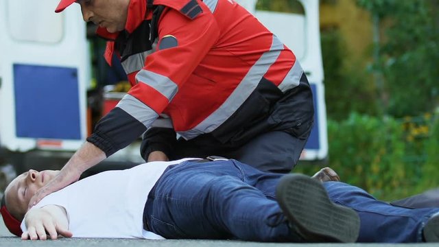 Paramedic crew running to man lying on road, first aid after accident, ambulance