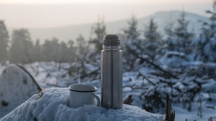 hot tea thermos on snow stump