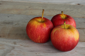 three apples on wood table