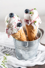 Homemade blueberries ice cream in waffle cones and fresh blueberries.