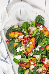 Salad. Spring vegetable salad. Fresh vegetable salad with grilled peach, pomegranate, spinach and fresh cheese