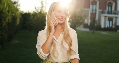 Close up of smiling attractive girl with long hair talking on mo