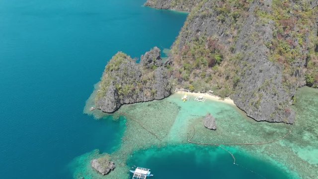 Aerial drone shot over turquoise lagoons, limestone cliffs and paraw boats, on a paradise isle, on a sunny day, at Coron island, Philippines, Asia