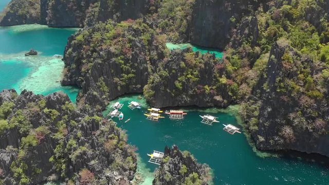 Aerial drone shot over turquoise lagoons, limestone cliffs and Paraw boats, on a sunny day in Coron island, Philippines, Asia