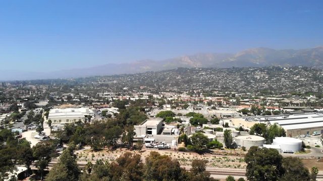 Aerial shot flying over the city buildings and luxury homes with mountains in the distance in downtown Santa Barbara.