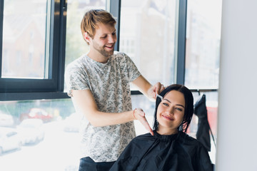 Obraz premium The hairdresser does a haircut with scissors of hair to a young girl in a beauty salon.