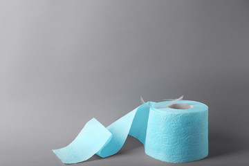 Roll of toilet paper with feather on grey background. Space for text