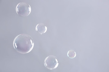 Beautiful translucent soap bubbles on grey background. Space for text